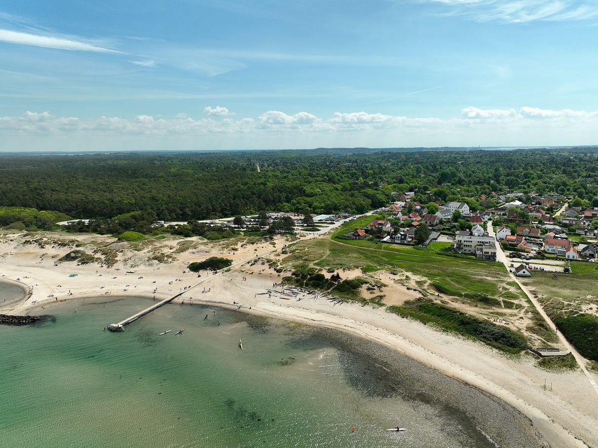 Bred kystlinje med strand, klitter og by set fra oven — Sjælland