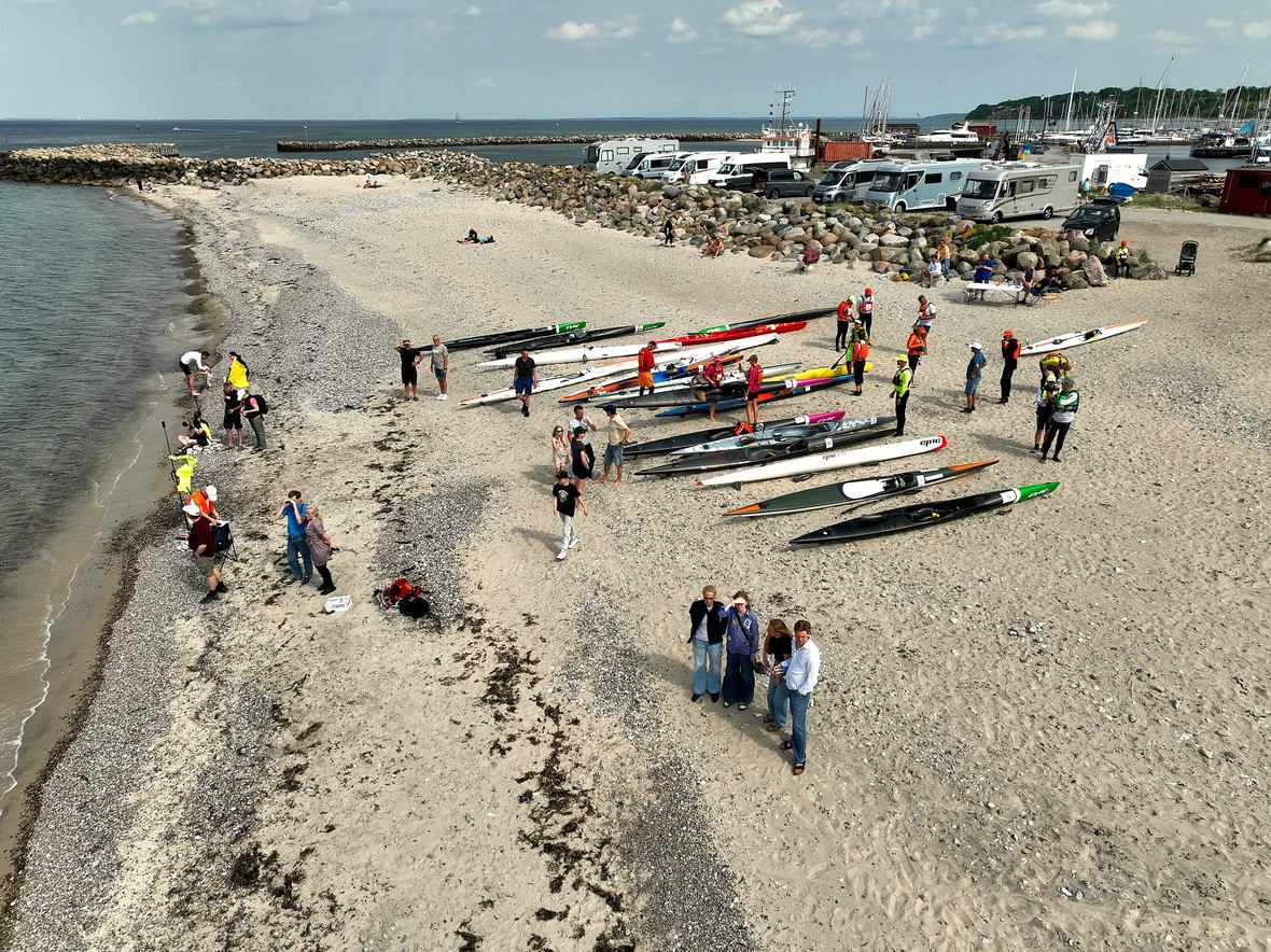 Kajakker og deltagere ved målstregen på stranden