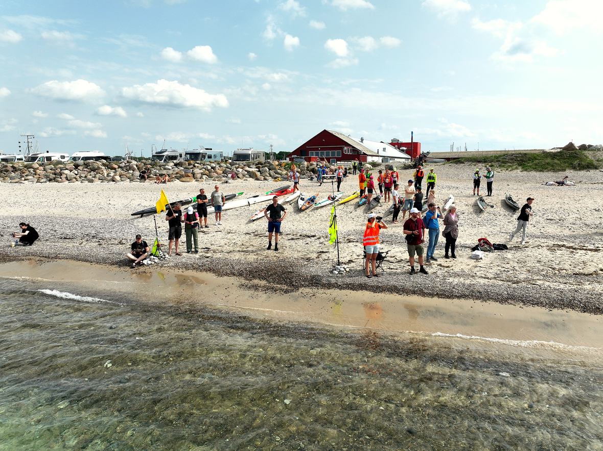 Tilskuere og kajakker langs vandkanten under Ocean Race